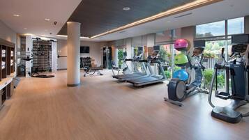 Un gimnasio moderno con cintas de correr, elípticas y pesas sueltas.
