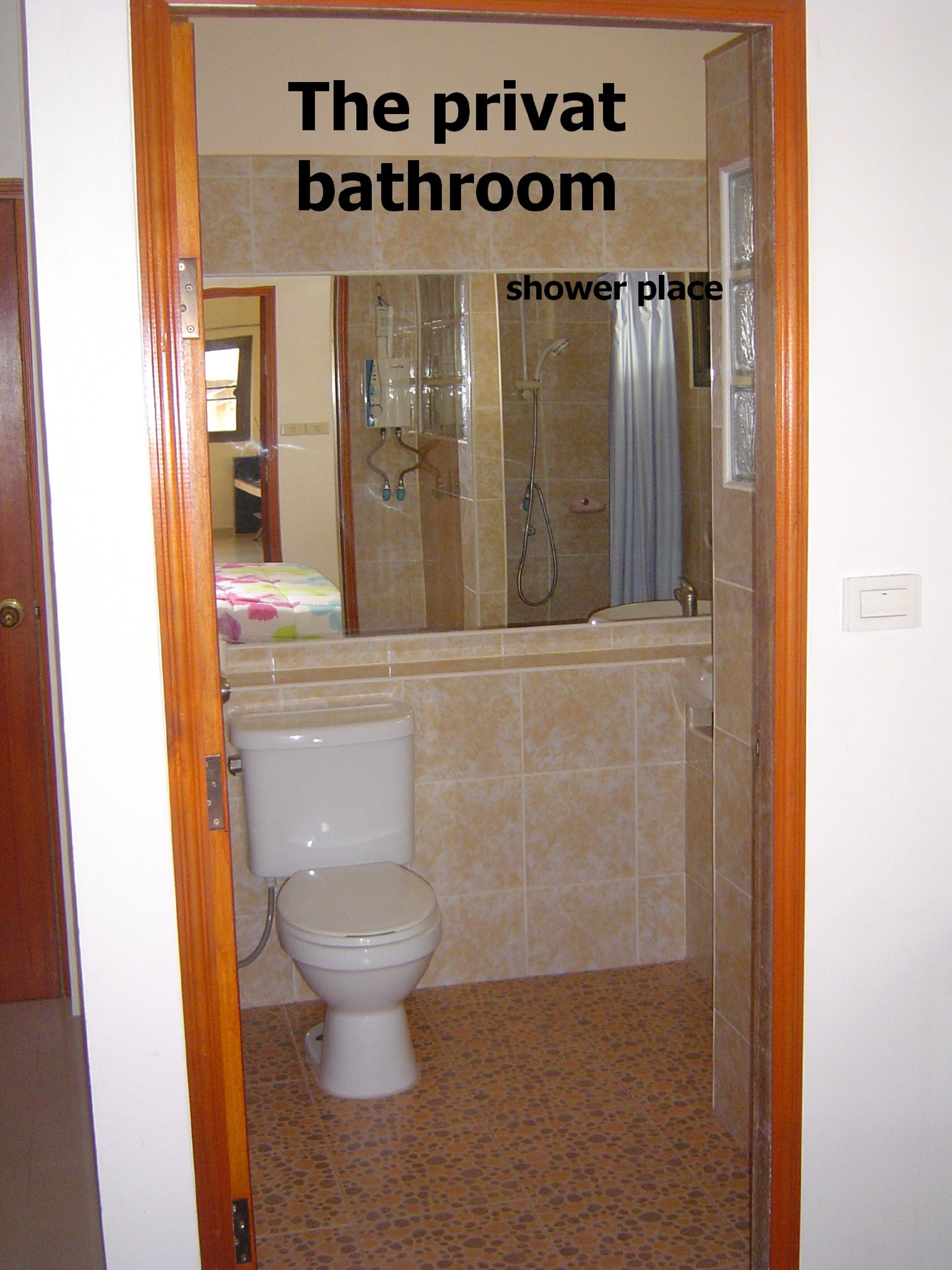A private bathroom with a toilet, shower area, and tiled walls.