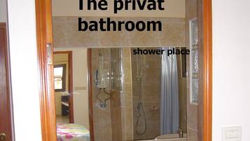 A private bathroom with a toilet, shower area, and tiled walls.