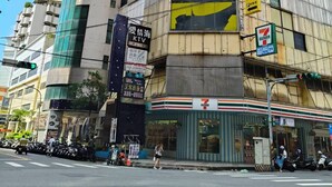 Un edificio de varios pisos con una tienda de conveniencia 7-Eleven en la planta baja.