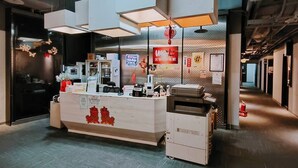 Un mostrador de recepción de diseño moderno, con una encimera blanca, una impresora y una pequeña decoración roja.