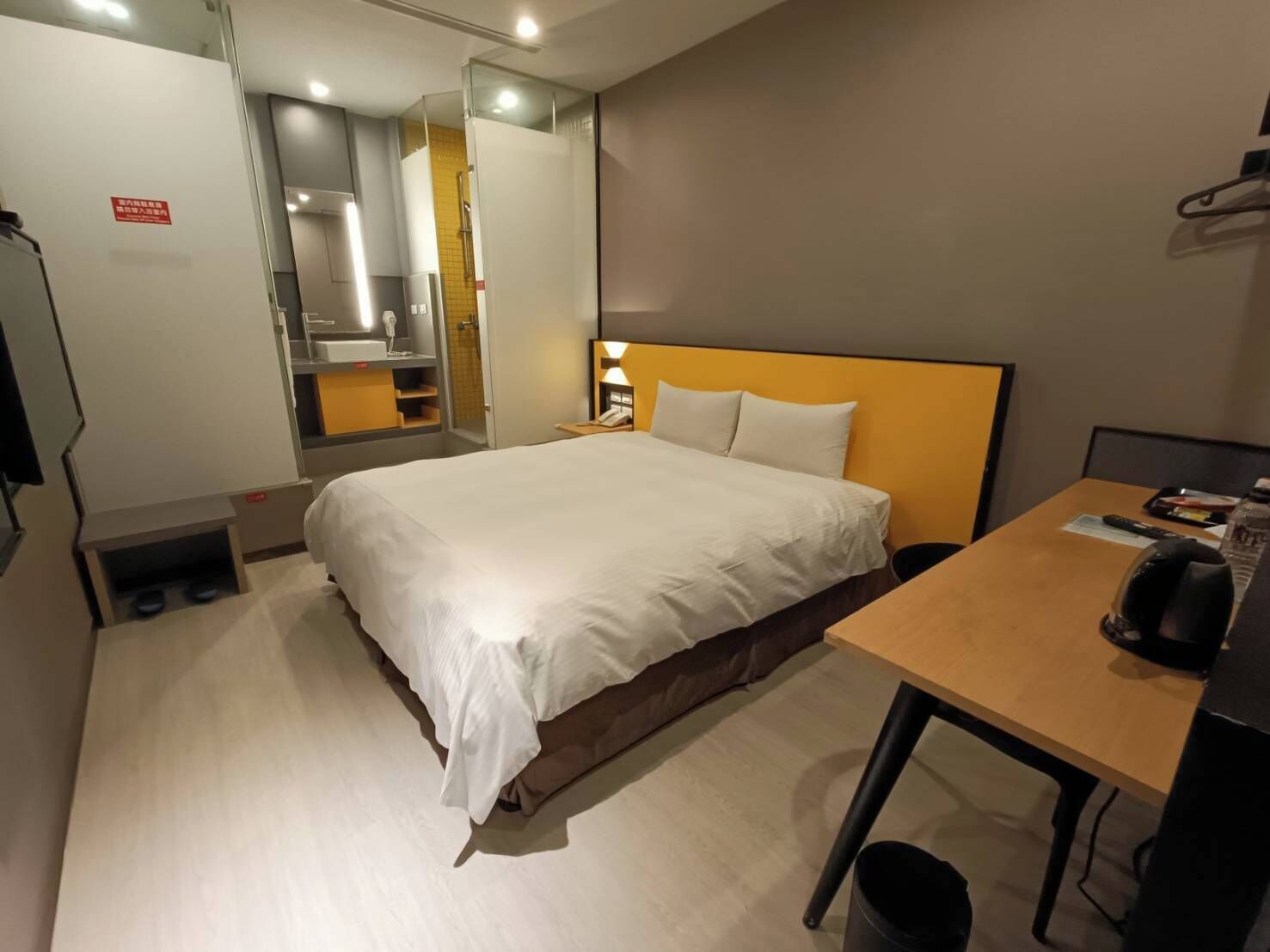 Habitación de hotel con cama, mesita de noche y espejo.