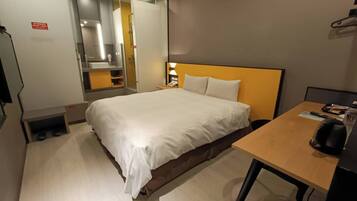Habitación de hotel con cama, mesita de noche y espejo.