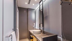 Un baño moderno con un lavabo redondo, un espejo grande y una ducha.
