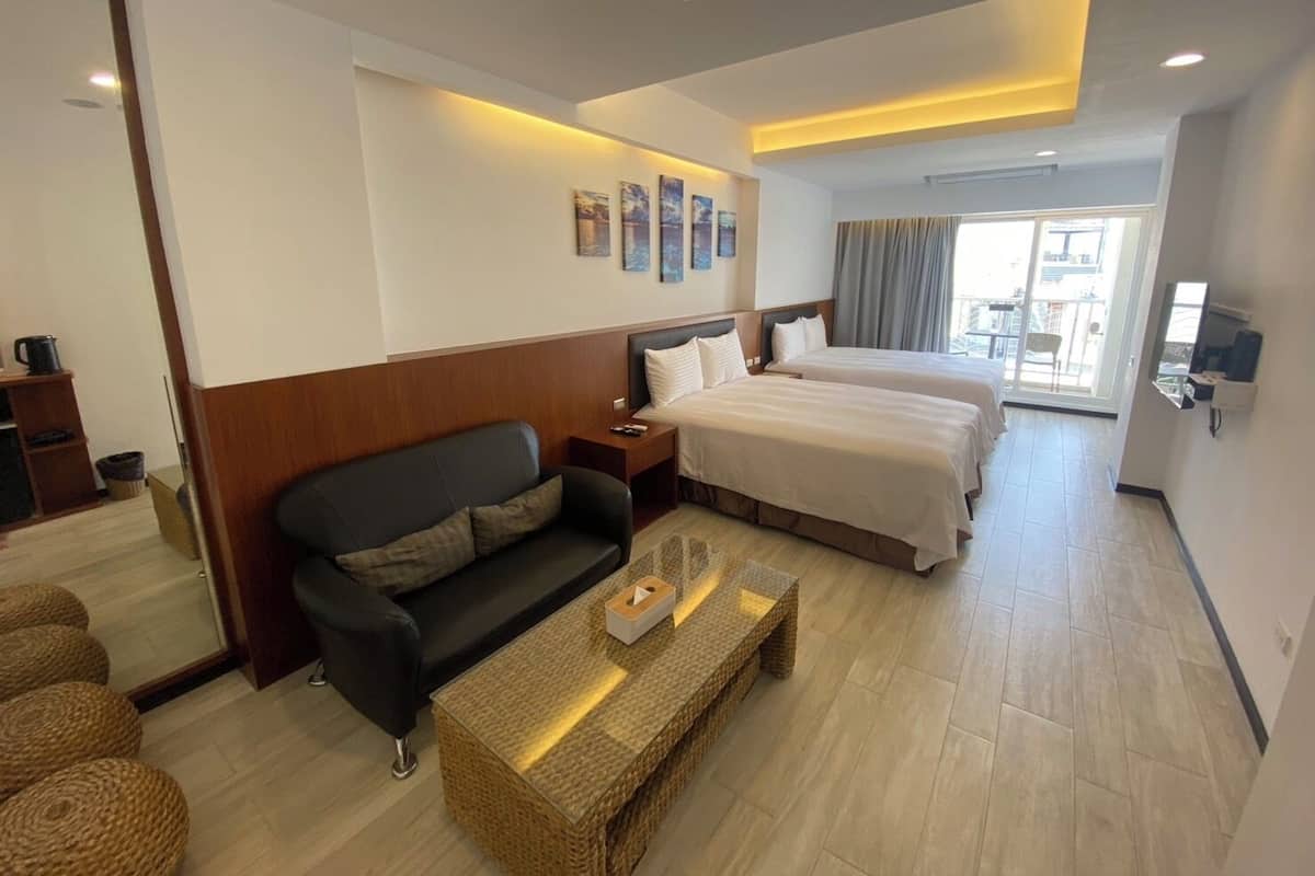 A hotel room with a bed, a sofa, a coffee table, and a TV.