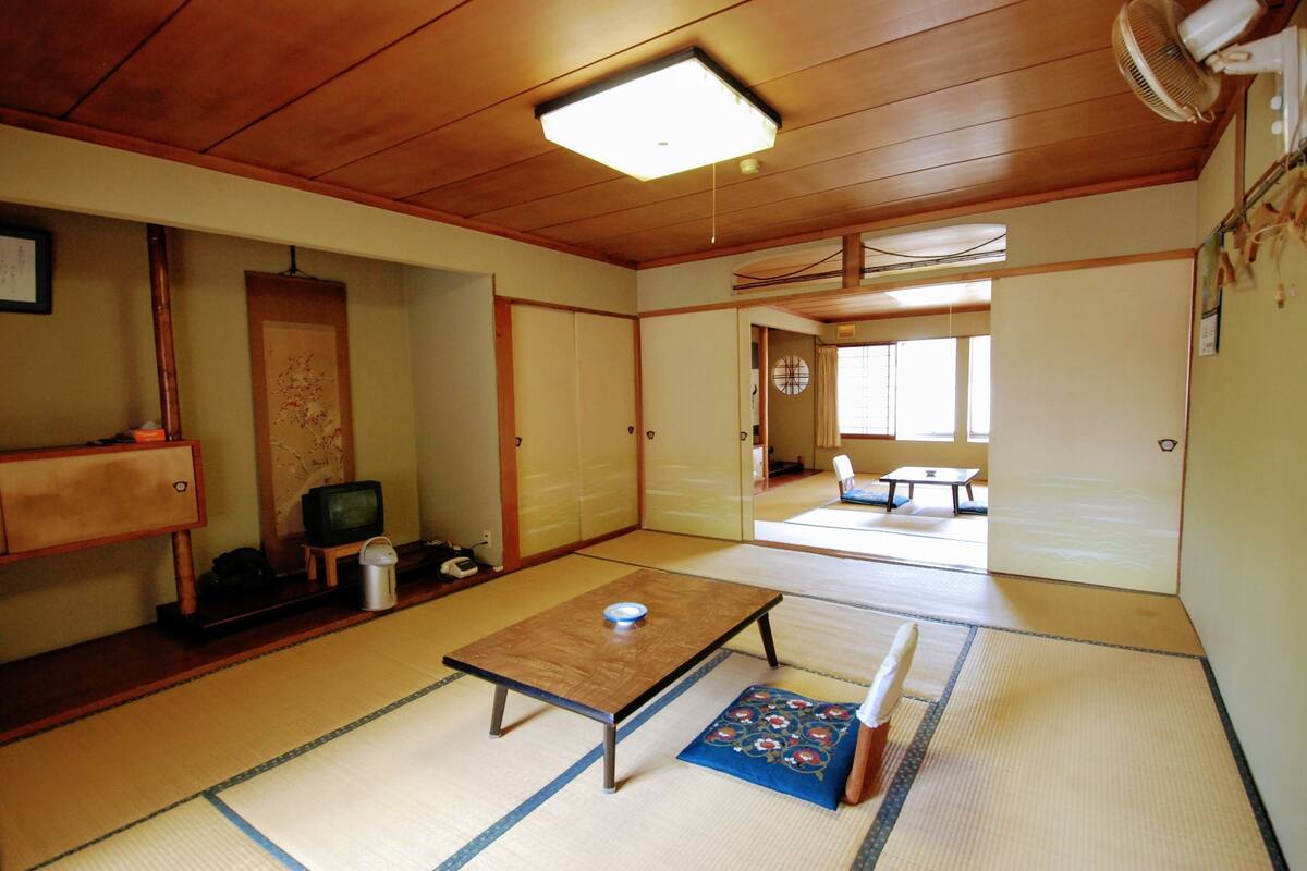 A traditional Japanese room with tatami flooring, a low table, a futon, and sliding doors.