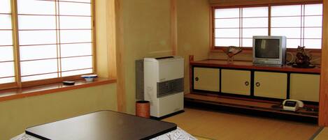 A traditional Japanese room with tatami flooring, a low table, a television, and a small cabinet.