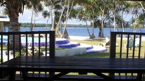 A wooden bench overlooking a beach with palm trees and a clear view of the ocean. - Bluepango Guest House - Hostel (Port Vila)