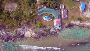 An aerial view of a coastal property with a swimming pool, a large house, and a separate building with a red roof. - Bluepango Guest House - Hostel (Port Vila)