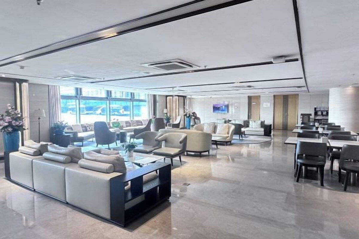 Un moderno vestíbulo de hotel con un área de estar, una recepción y un televisor.