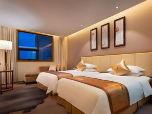 Habitación de hotel con dos camas, una mesita de noche, una lámpara y una ventana con cortinas.