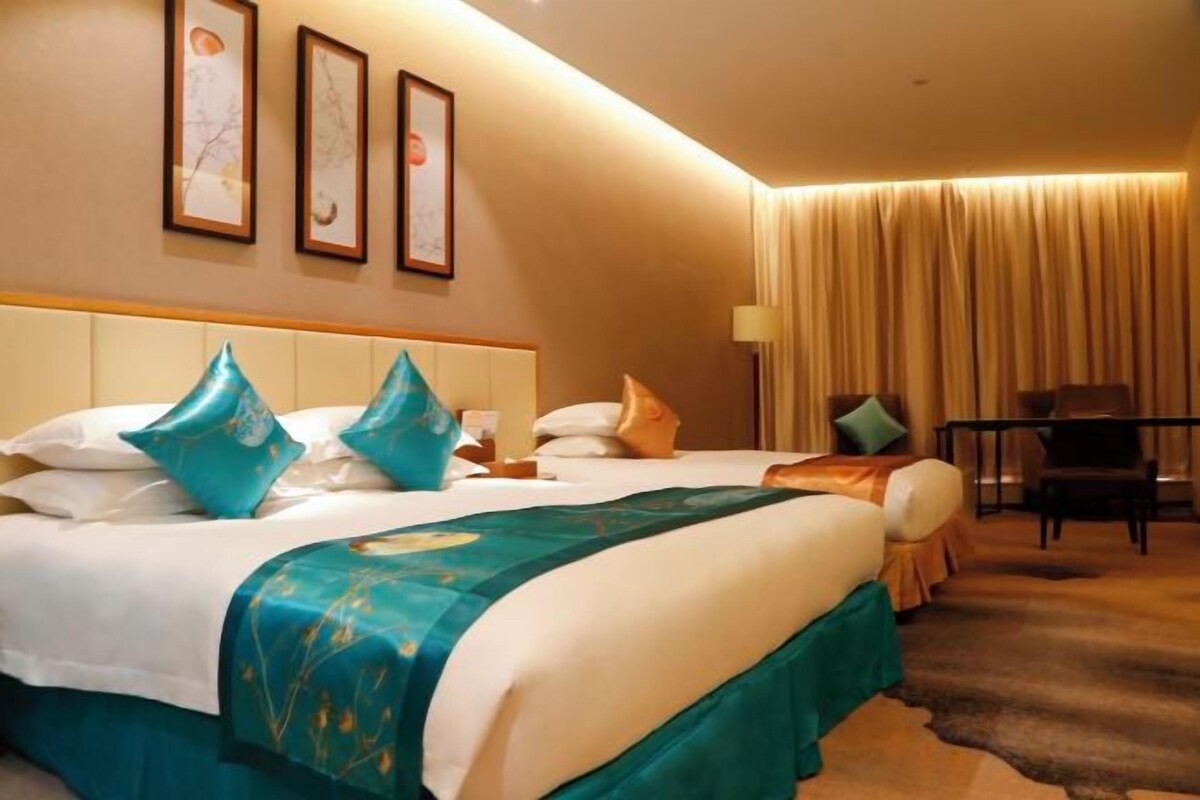 A hotel room with a large bed, a desk, and a chair.