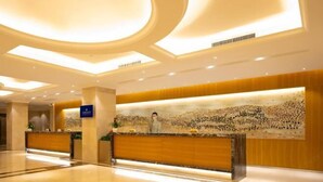 A hotel reception area with a modern design, featuring a reception desk, a large wall mural, and a polished floor.