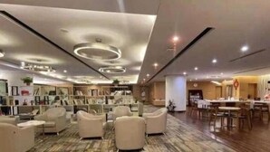 Un vestíbulo de hotel con área de descanso, una recepción y una estantería.