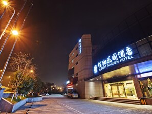 L’entrée d’un hôtel, avec une enseigne indiquant « FLIPORT GARDEN HOTEL », et un parking situé devant.