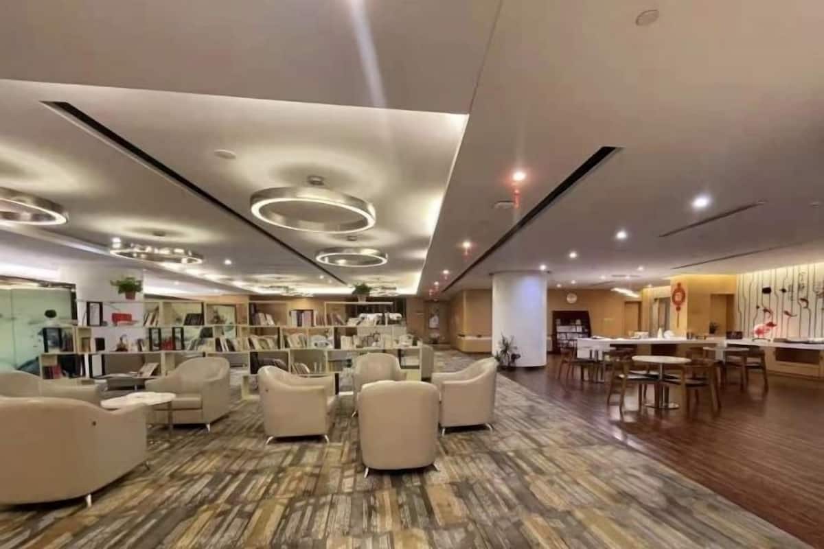 Un hall d’entrée spacieux, doté de meubles modernes, d  ’un tapis à motifs et d’un plafond bien éclairé, agrémenté de luminaires circulaires.