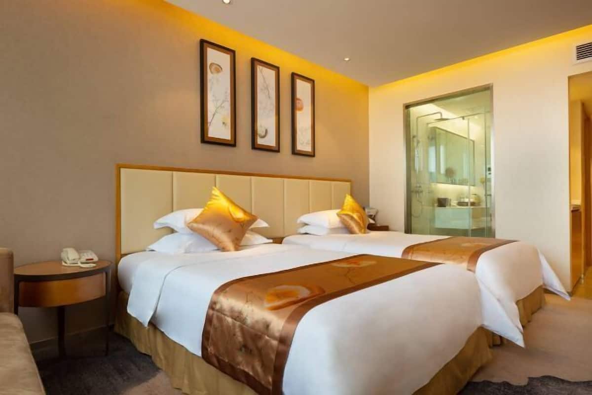 Une chambre d’hôtel avec deux lits, une table de chevet avec un téléphone et des œuvres d’art encadrées au mur.
