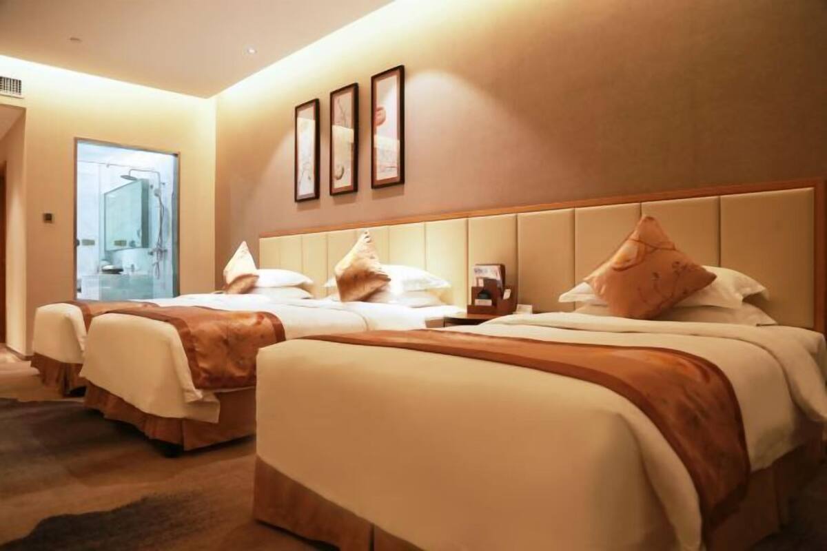 Une chambre d’hôtel avec deux lits, une grande fenêtre et un téléviseur fixé au mur.