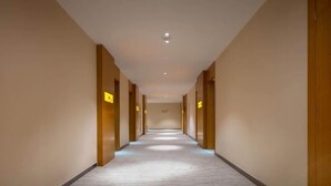 A long, narrow hallway with a patterned carpet and wooden doors on either side.