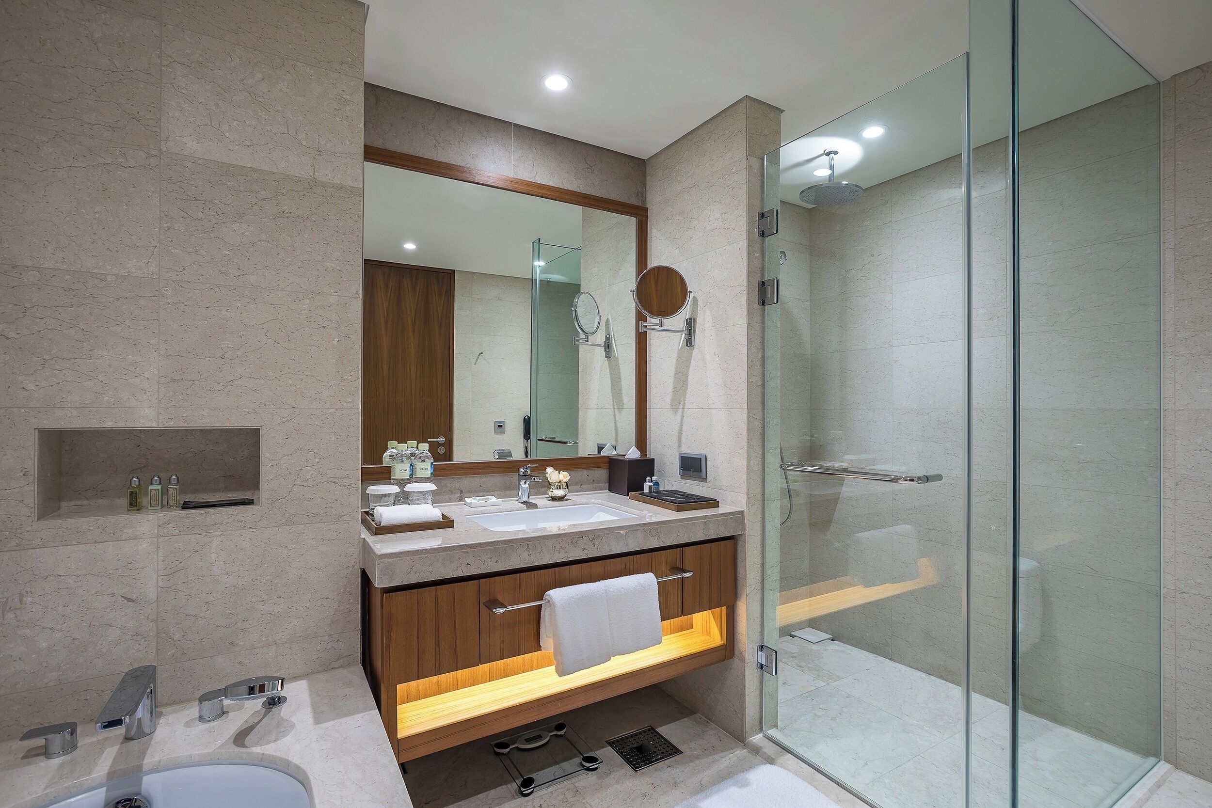 A modern bathroom with a glass-enclosed shower, a vanity with a mirror, and a sink.