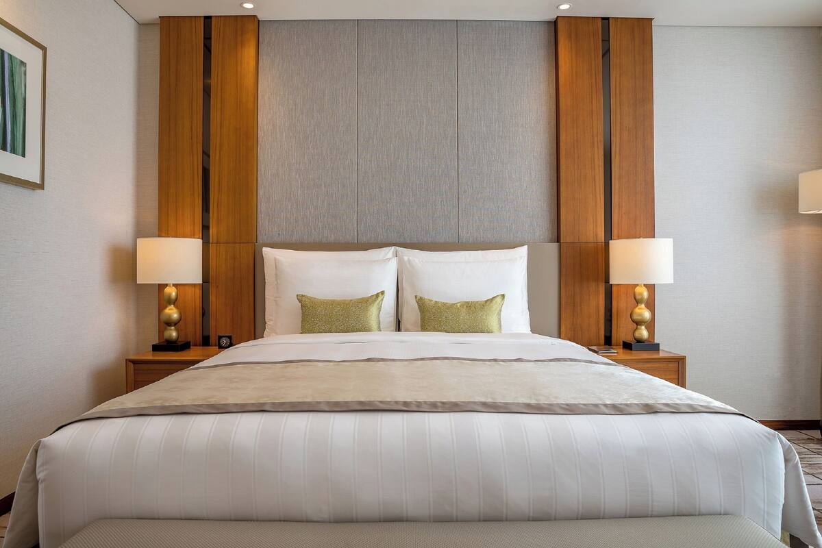 A hotel room with a large bed, two bedside lamps, and a wooden headboard.