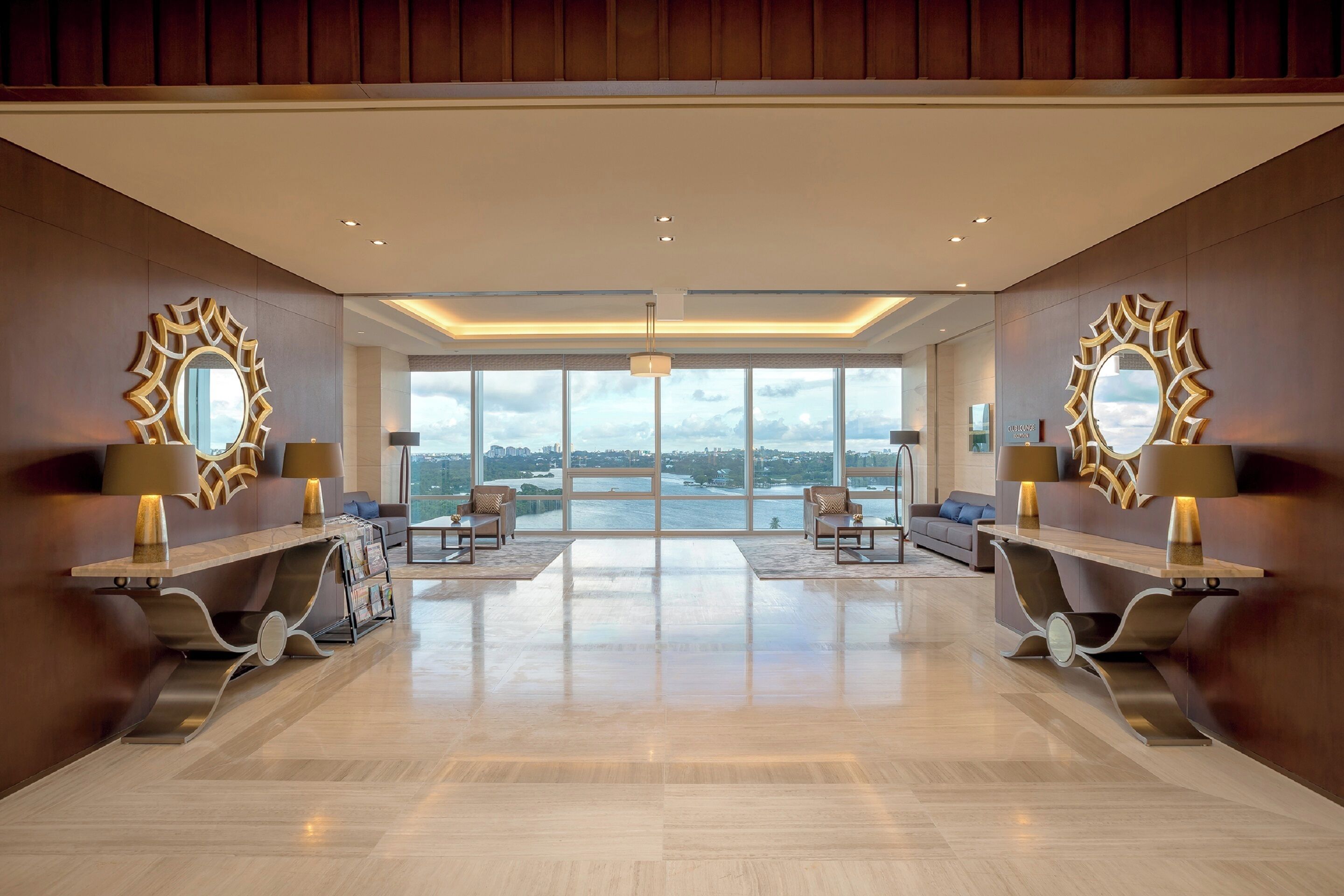A spacious lobby with a modern design, featuring a reception desk, seating area, and large windows offering a view of the city.