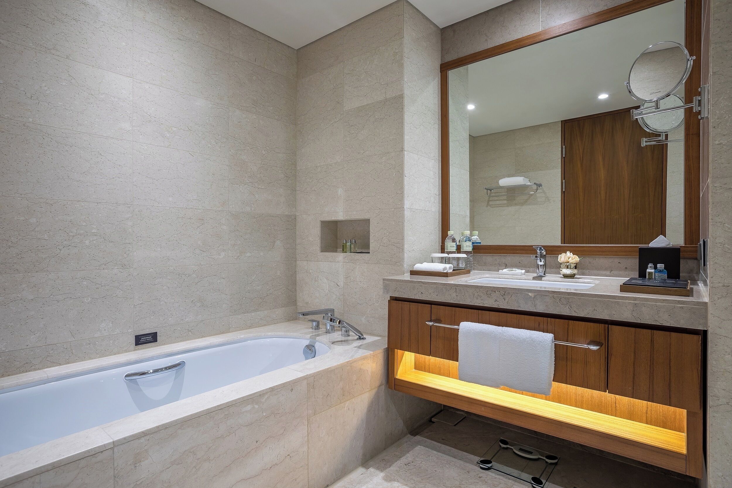 A modern bathroom with a large bathtub, a vanity with a mirror, and a wooden cabinet.