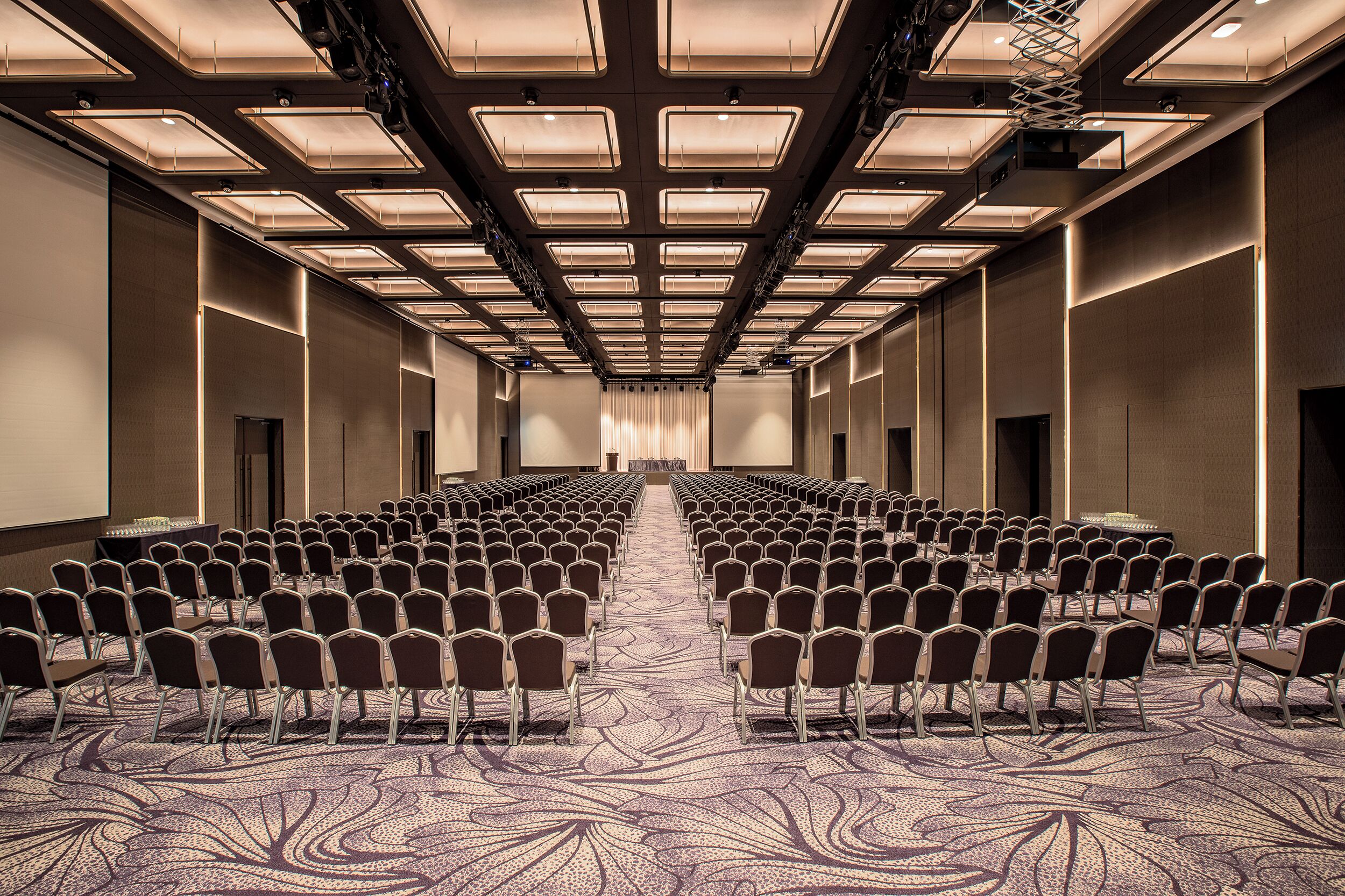 Une salle de conférence avec des rangées de chaises et un sol recouvert de moquette.