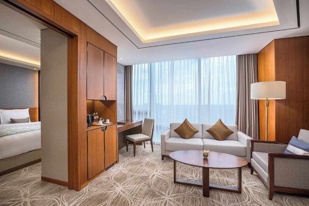A hotel room with a bed, a sofa, a desk, and a chair.