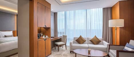 A hotel room with a bed, a sofa, a desk, and a chair.