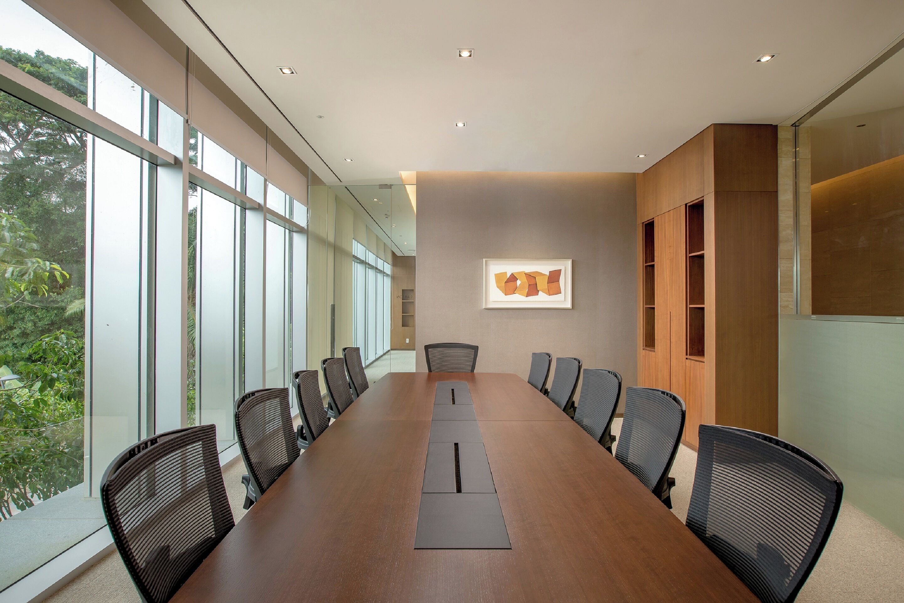 Une salle de conférence avec une longue table, des chaises et une grande fenêtre.