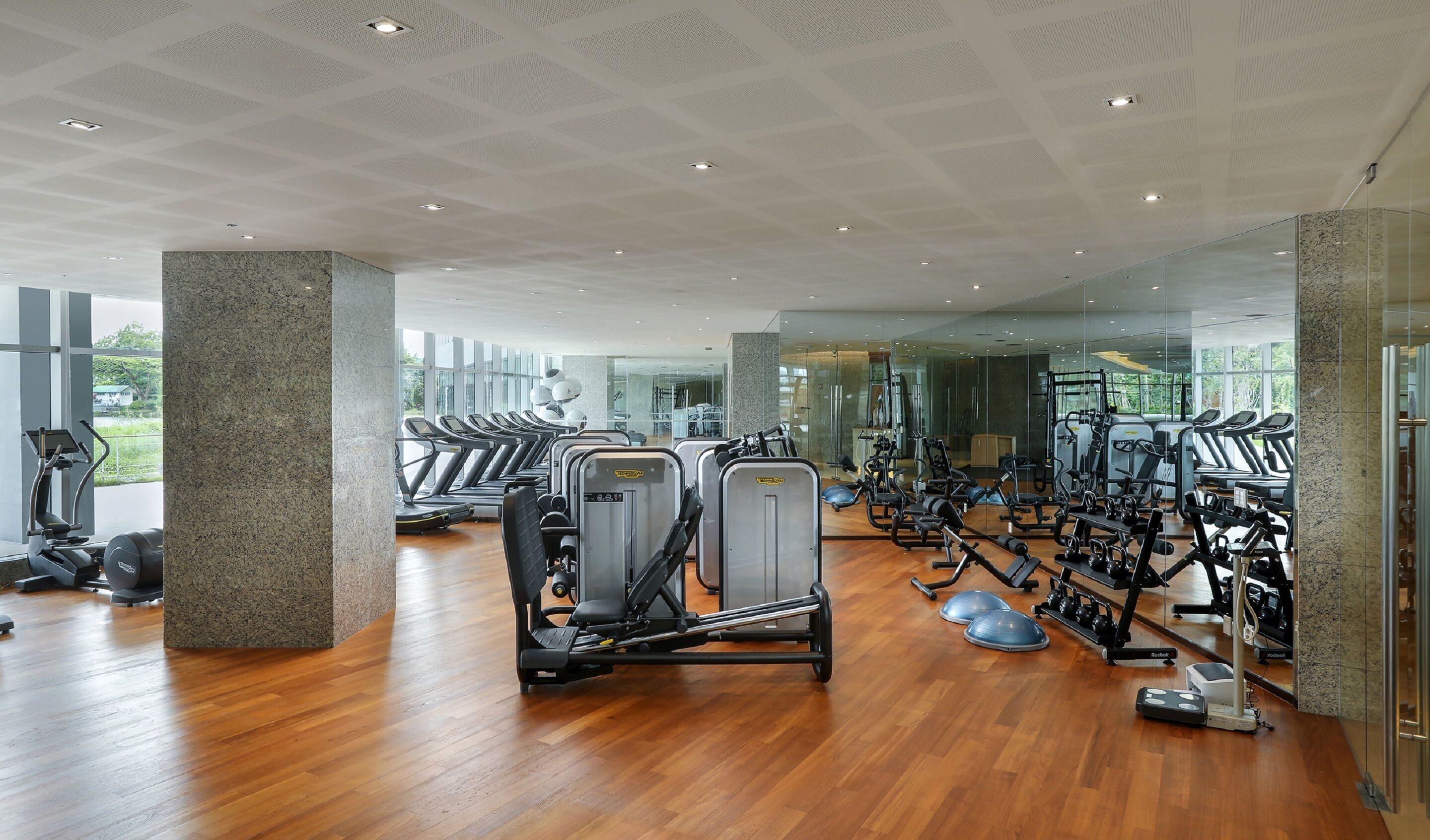 Een fitnessruimte met loopbanden, krachtapparaten en elastiekjes.