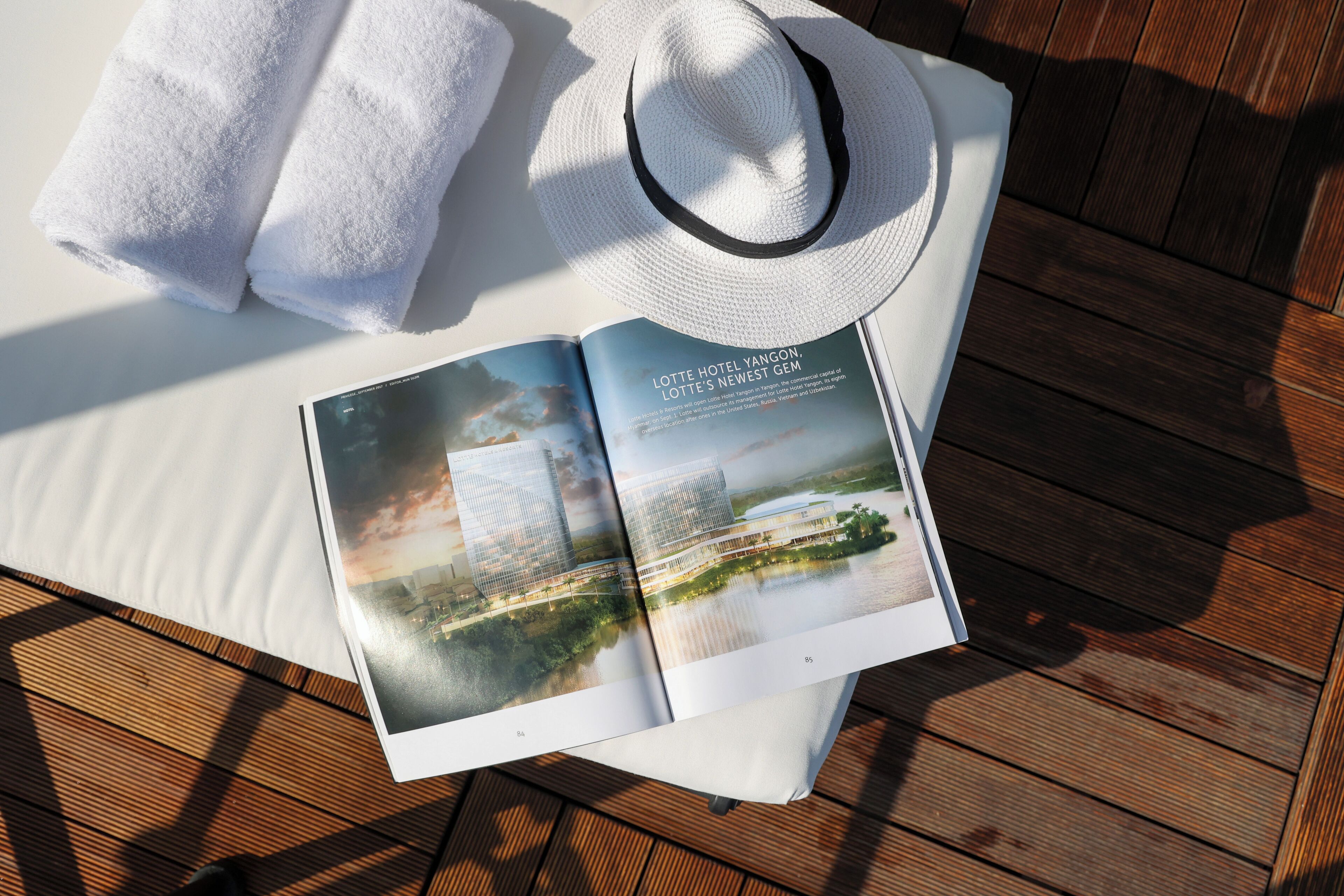 A book open on a wooden surface, a white towel, and a white hat.