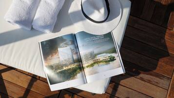 A book open on a wooden surface, a white towel, and a white hat.