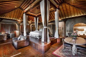 Una habitación amplia con techo alto, una cama grande, zona de estar y una mesa de comedor.