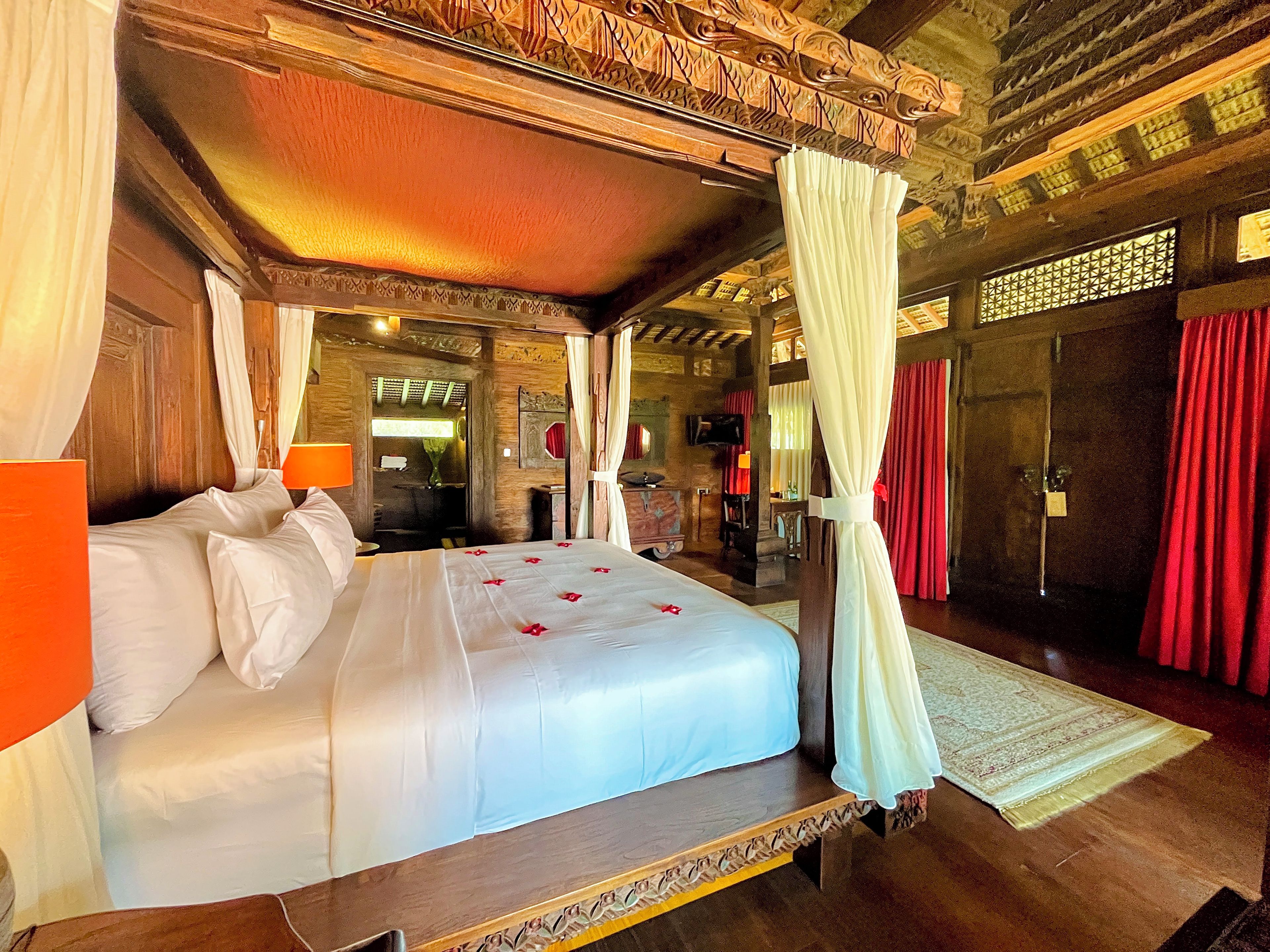 Un letto a baldacchino con tenda, una testiera in legno e uno specchio grande sopra.