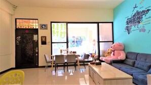 A cozy room with a dining table, chairs, a sofa, and a large teddy bear. - Have FUN villa (Hengchun)
