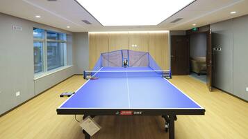 A ping pong table in a room with wooden flooring, a window, and a door.