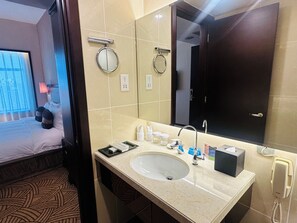 A hotel bathroom with a large mirror, a sink, a towel rack, a toilet paper dispenser, and a telephone. - Celebrity International Grand Hotel (Beijing)