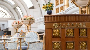 En elegant hotellobby med detaljeret møblering, en stor reception og en overdådig blomsterdekoration.
