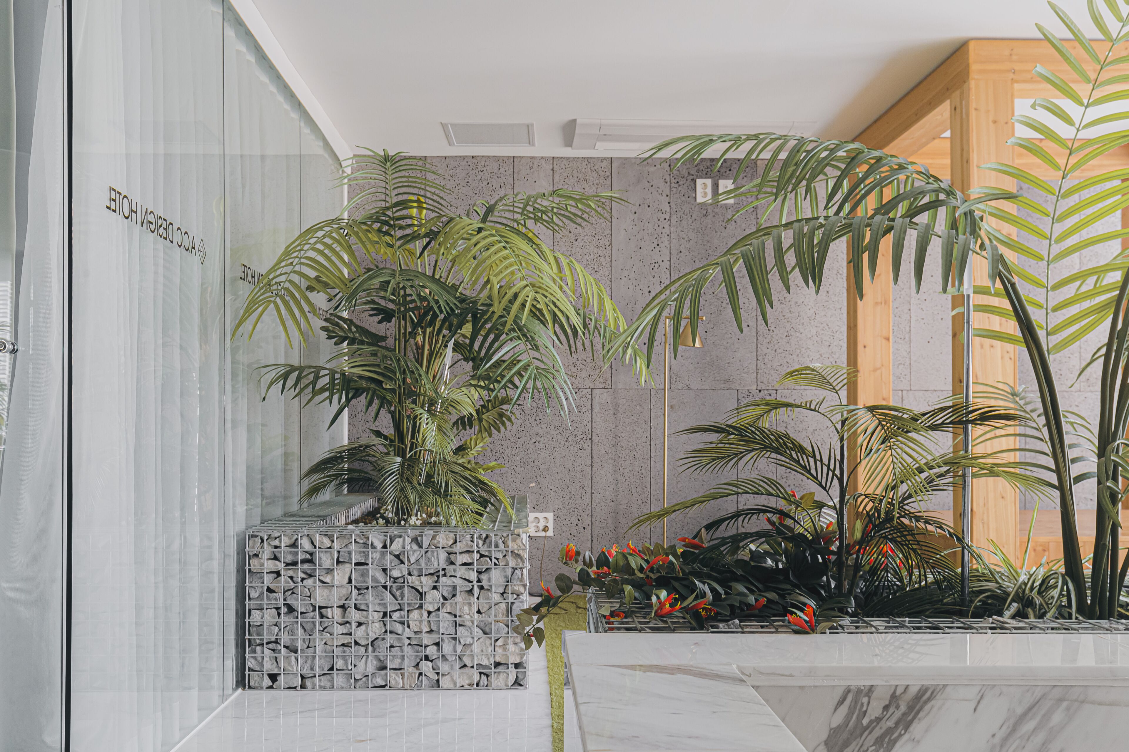 Zona de recepción con una jardinera de piedra, plantas en macetas y un mostrador de mármol.