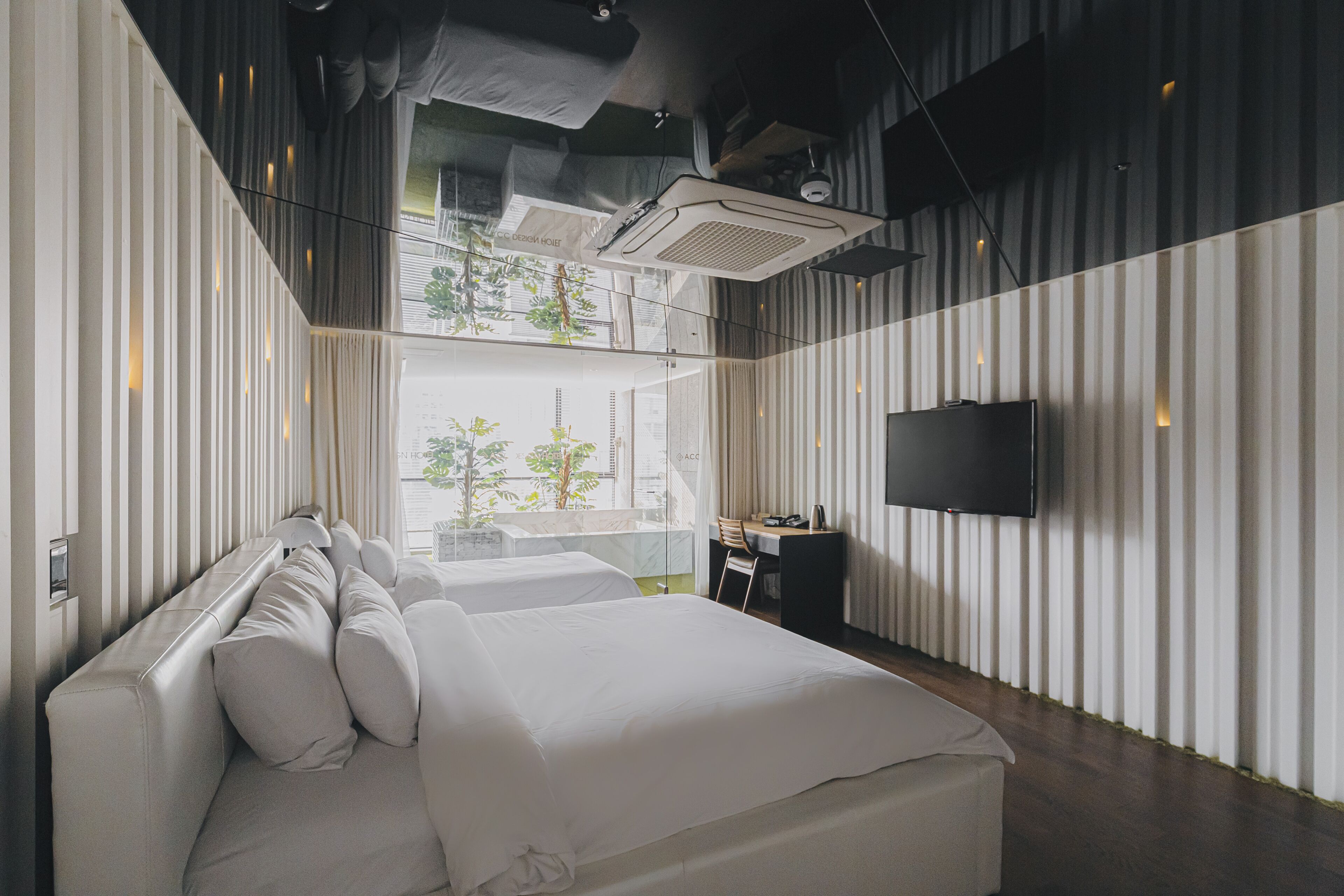 A modern hotel room with a large bed, a desk, and a TV.
