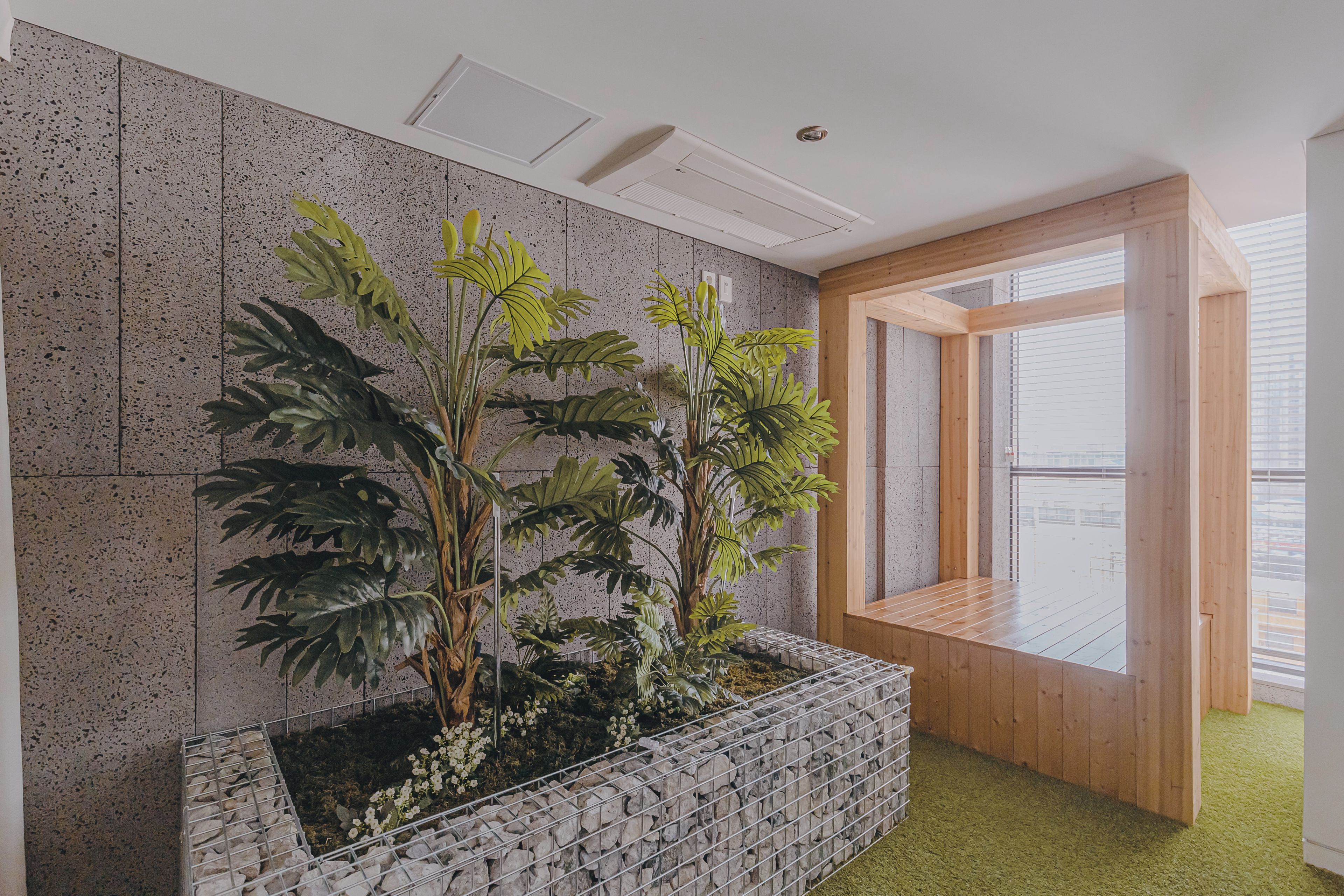 A room with a stone wall, a wooden bench, and a window with blinds.