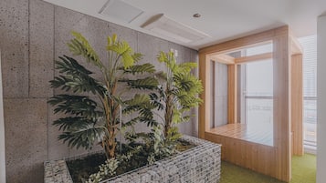 A room with a stone wall, a wooden bench, and a window with blinds.