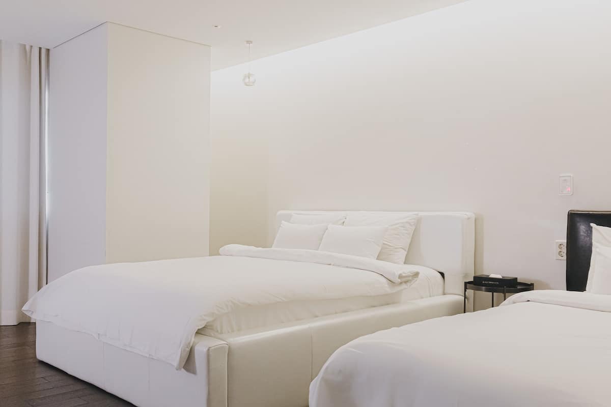 Habitación de hotel con dos camas, una mesita de noche y una lámpara fijada a la pared.