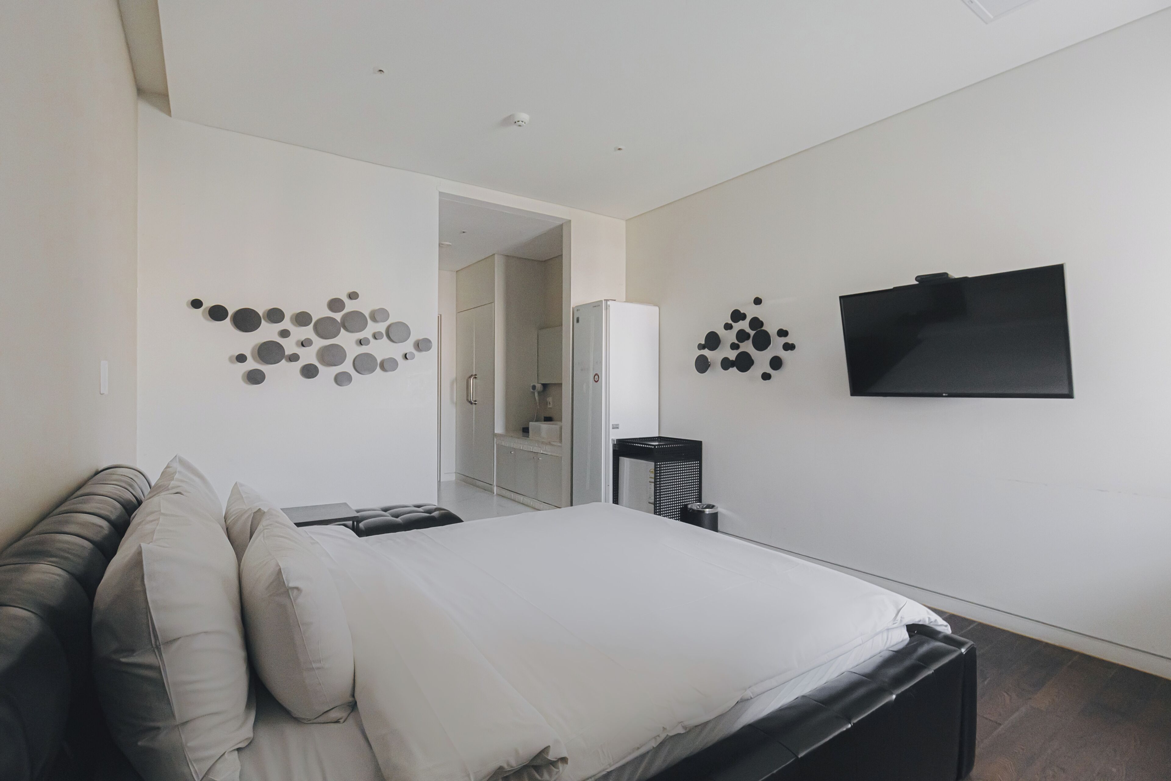 A modern bedroom with a bed, a TV, and a wall-mounted TV.