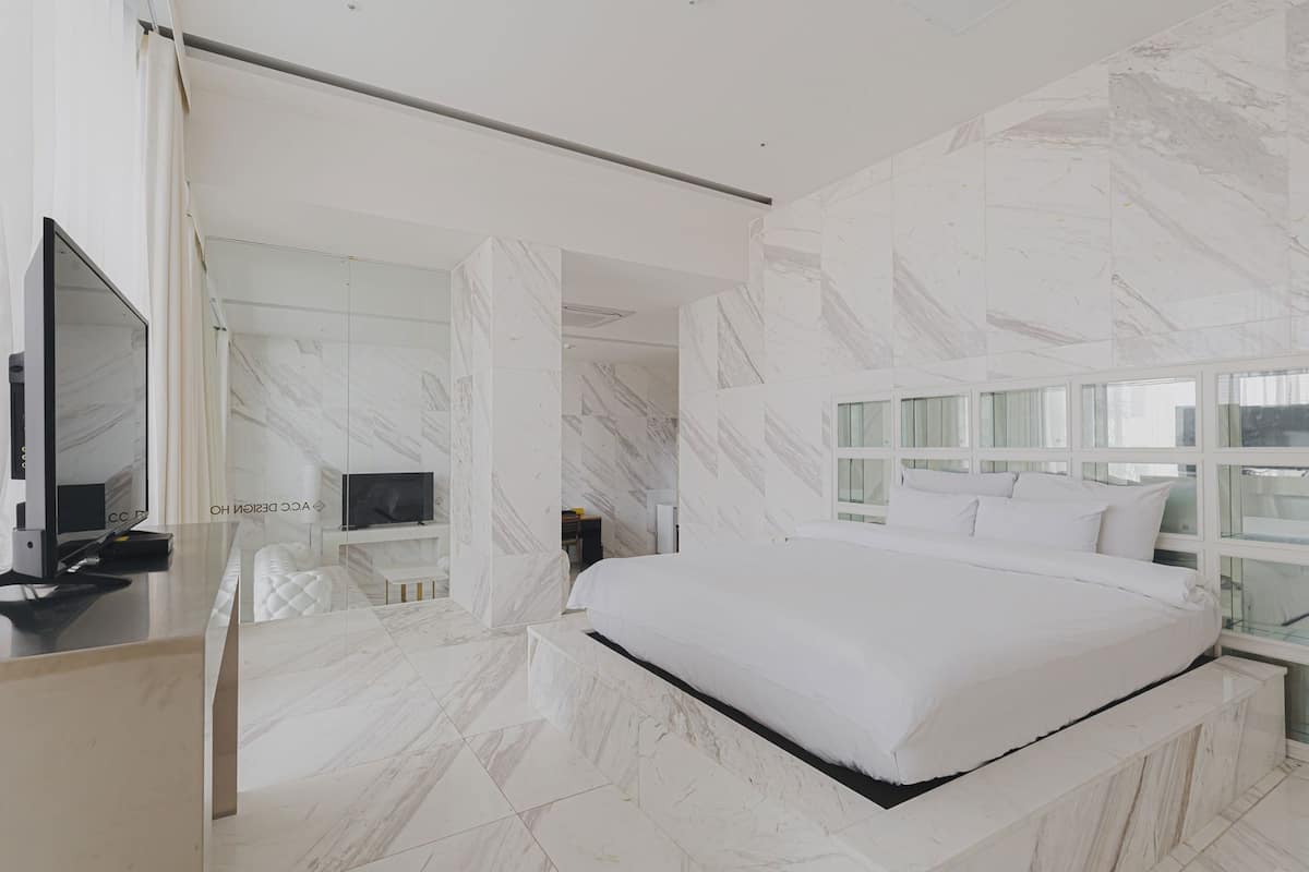 Un dormitorio moderno con una cama grande, un televisor y suelo de mármol.