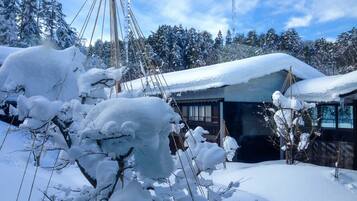 Un paysage enneigé avec une cabane en bois et un grand arbre au premier plan.