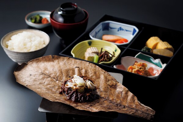 Un repas traditionnel, présenté sur un plateau avec différents plats, notamment du riz, des légumes et un plat principal servi sur une feuille.