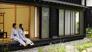 A traditional Japanese building with a sliding door and a stone pathway leading to a seating area. - Hotel Kikori (Hida)